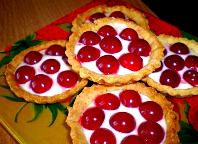 1. Этап. Корзиночки с вишней: Но не забываем, что корзиночки-то у нас с вишней. У меня есть отличная свежая ягода, которую даже варить жалко. Хочется ее есть прямо так, в натуральном виде, чтобы извлечь из нее максимум витаминов. Вы, конечно, можете использовать вишневое варенье. Итак, начиняем наши корзиночки. Достаем сметанный крем и кладем по 1-2 чайной ложки в каждую тарталетку. Вымытую и обсушенную вишню освобождаем от косточек. Делаем это осторожно, не помяв ягоды. Вкладываем вишни в сметанный крем. Корзиночки с вишней готовы! Их можно подавать с чаем, кофе, какао и кефиром.