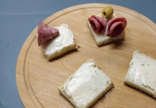 1. Этап. Мини-бутерброды Ассорти: Ломтик хлеба разрезать на 4 части, намазать плавленым сыром.