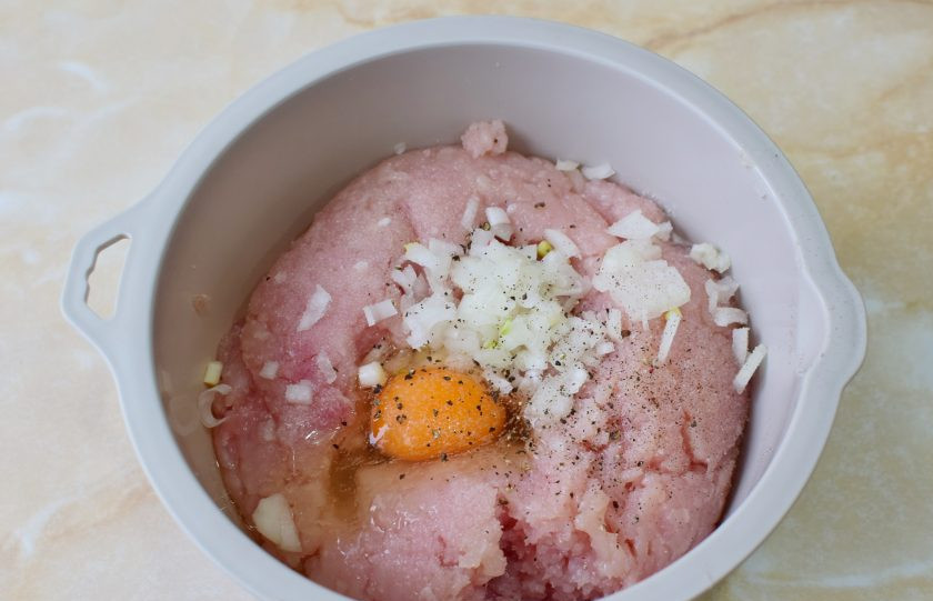 1. Этап. Куриные котлеты с начинкой из сыра и зелени: Куриный фарш выложите в чашу. Добавьте к нему мелко нарезанный лук и яйцо. По вкусу подсыпьте соль и специи. Перемешайте. Затем отбейте фарш о дно чаши, чтобы сделать его плотнее. Это необходимо для того, чтобы котлеты не разваливались при жарке.