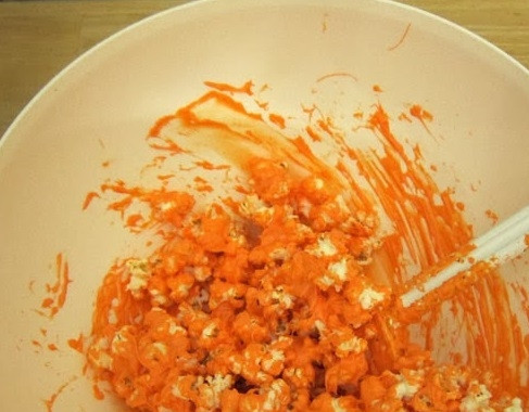 1. Этап. Монстры из попкорна на Хэллоуин: 1. Попкорн или кукурузные палочки выложите в большую миску. На плите растопите масло, введите туда ириски и, помешивая, растопите ириски в масле до жидкой однородной массы. Полученной горячей массой залейте попкорн или кукурузные палочки.