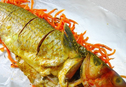 1. Этап. Кефаль в духовке в фольге: Сверху на морковь укладываем рыбину, и делаем надрезы.