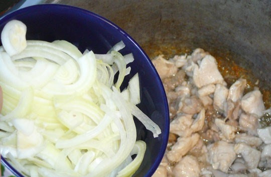 1. Этап. Каша рисовая со свининой: Свинину вымойте и нарежьте на равные кусочки. Вы можете взять любую часть. Если предпочитаете диетическое мясо, то выбирайте вырезку, а если нет — то подойдет и шея. Мясо должно быть очищено от кожицы, пленок, жилок. Поставьте казанок на небольшой огонь на плиту, влейте растительное масло без запаха. Когда оно разогреется, выложите в казан мясо. Обжаривайте его до румяной корочки. Репчатый лучок очистите от шелухи. Вымойте его и порубите полукольцами шириной 0,5 см. Добавьте к мясу и обжаривайте, периодически помешивая, пока лук не станет мягким и прозрачным.