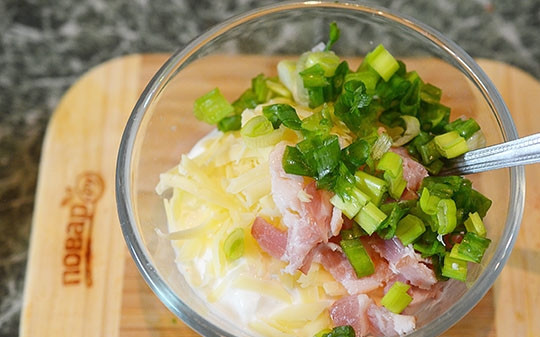 1. Этап. Чипсы из картофеля в мундире с дипом: Сделайте дип. Смешайте сметану, крем-чиз, нарезанный лук и бекон и тёртый сыр. Посолите.