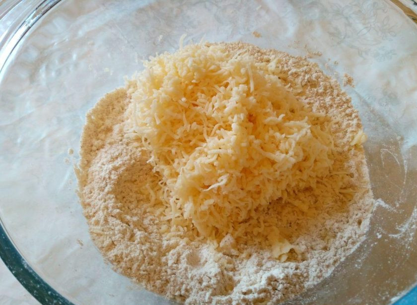 1. Этап. Квише с овощной начинкой: Сыр натрите на мелкой тёрке и добавьте половину указанного количества (100 грамм) к сухим компонентам, перемешайте.