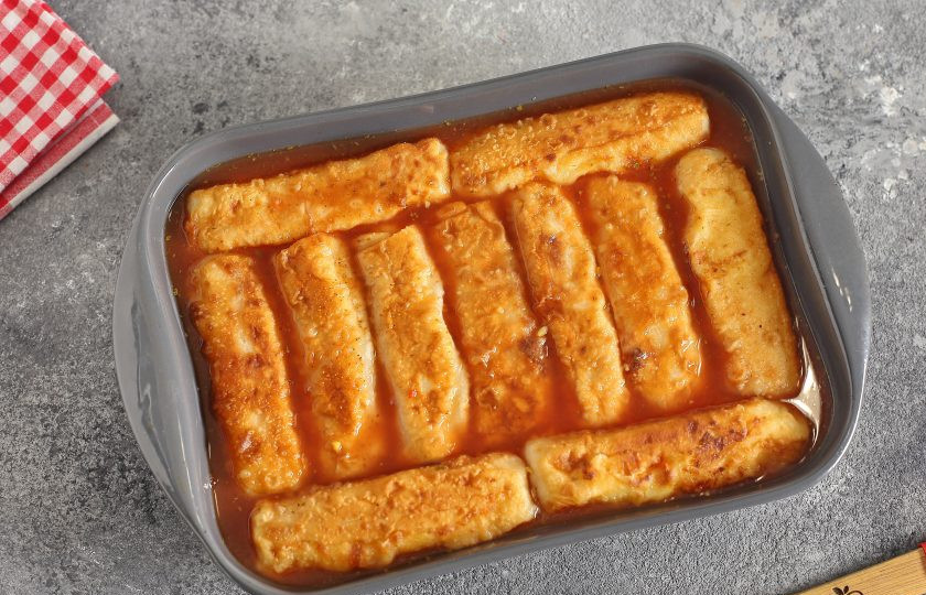 1. Этап. Рулетики из теста с картошкой: Сверху разложите рулетики и залейте их водой, разбавленной с томатной пастой (не забудьте добавить соль по вкусу). Можно рулетики предварительно не обжаривать, но тогда их выкладывайте на некотором расстоянии друг от друга, так как они в таком случае увеличатся в размере. Запекайте в духовке при температуре 180 градусов около 25 минут.