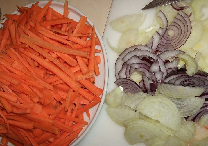 1. Этап. Плов из индоутки: Морковь помыть, почистить и нарезать длинной соломкой. Для этого сначала режем морковь вдоль на пластины толщиной примерно 4 милиметра, затем каждую пластину — соломкой. Лук очищаем и режем полукольцами или кольцами толщиной 5 милиметров.