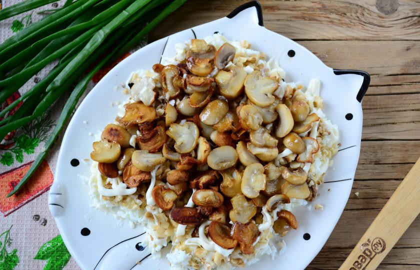 1. Этап. Салат Желтая собака: Следующий слой - обжаренные грибы. Сверху - сеточка майонеза.