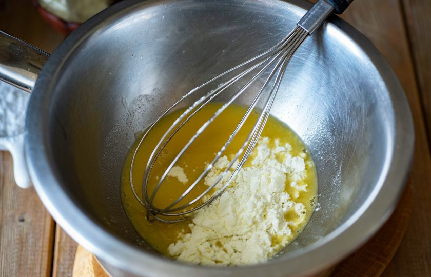 1. Этап. Белый шоколад из какао масла: Снимите водяную баню с огня и в миску с растопленным какао маслом добавьте сухое молоко, вмешайте его венчиком в растопленное какао масло.