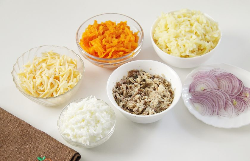 1. Этап. Мимоза на Новый год в виде свинки: Отделите у яиц белки от желтков и натрите на крупной терке (желтки нам понадобятся чуть позже). Также на крупной терке натрите морковь, картофель и сыр. Консервы откройте, слейте большую часть масла и разомните рыбу вилкой. Лук нарежьте тонкими полукольцами.