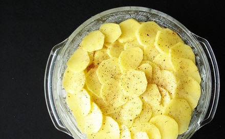 1. Этап. Картошка в сметане: Смазываем форму для запекания сливочным или растительным маслом. Картофель нарезаем тонкими пластинками и смешаем с измельченным чесноком, выкладываем картофель в форму, посыпая слои солью, перцем и специями.