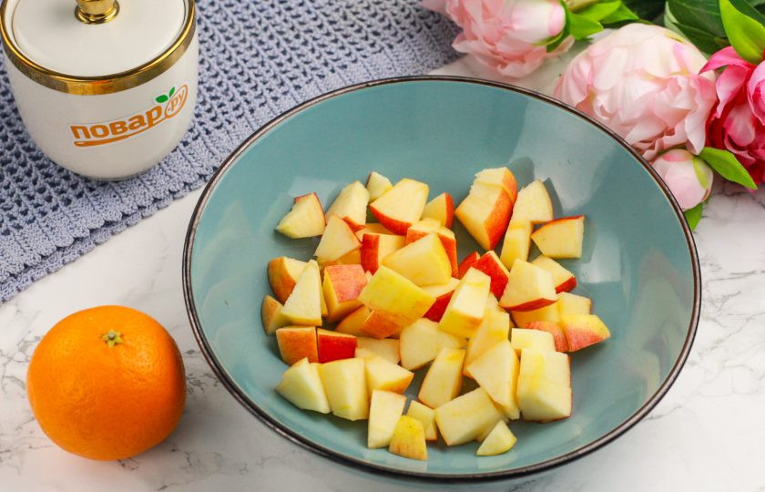 1. Этап. Салат с мандарином, яблоком и апельсином: Яблоко промойте в воде, разрежьте на четыре части и вырежьте семенные блоки. Нарежьте кубиками и высыпьте нарезку в салатник.