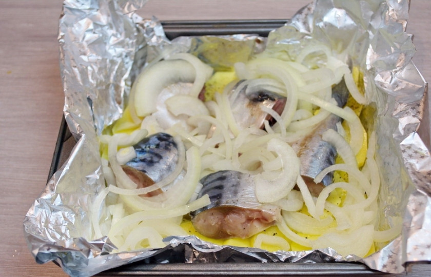 1. Этап. Скумбрия кусочками в духовке: Кусочки рыбки уложите поверх картофеля, предварительно посолив и поперчив. Репчатый лук нарежьте полукольцами. Выложите на рыбку.