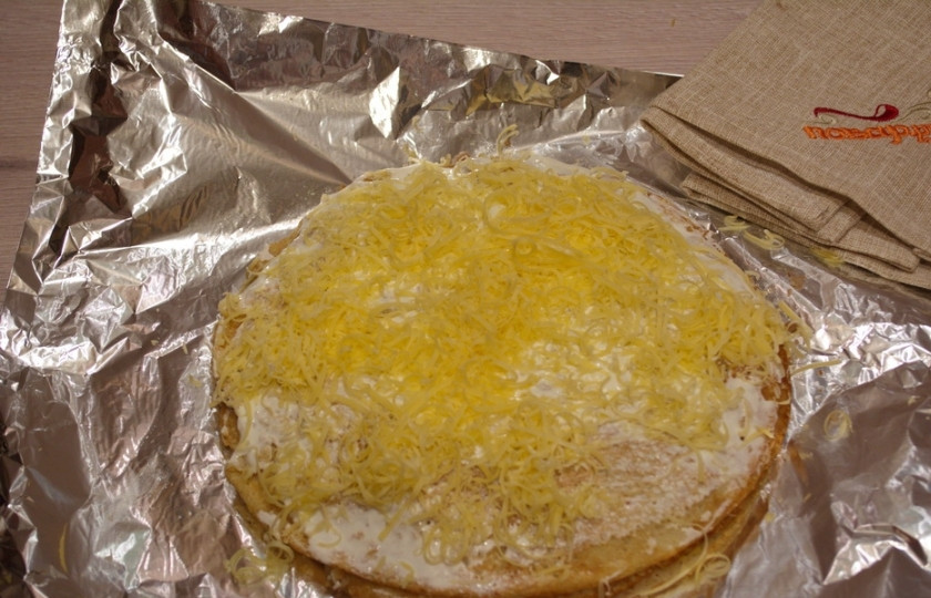 1. Этап. Блинный пирог с фаршем: Накройте новым блинчиком и снова выложите фарш. На фарш выложите натертый сыр, потом снова блин и снова фарш — и так до завершения процесса. Накройте завершающим блином. Сам блин смажьте сверху сметаной. Посыпьте тертым сыром. Разогрейте духовку до 200 градусов и запеките получившийся пирог около 10-12 минут.