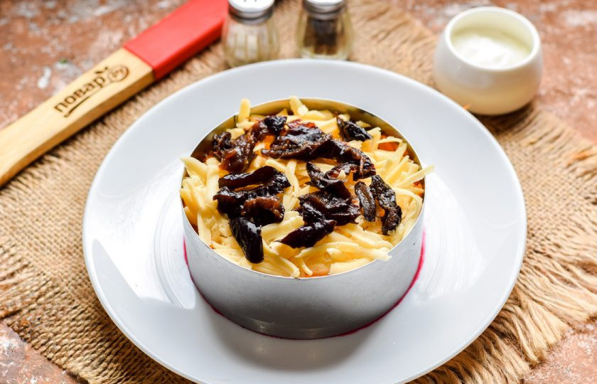 1. Этап. Салат Чингисхан со свеклой: Чернослив нарежьте небольшими кусочками и выложите поверх сыра.