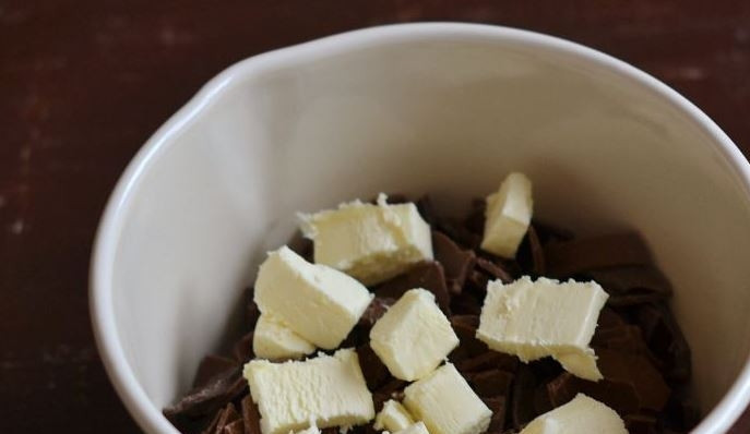 1. Этап. Конфетки: Холодное сливочное масло порубите на куски и выложите в сотейник к черному шоколаду. Влейте в сотейник молоко.