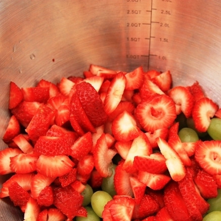 1. Этап. Фруктовый салат с медовым сиропом: Клубнику нарезаем на крупные дольки и добавляем к винограду.