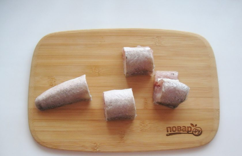 1. Этап. Диетическая рыба с овощами: Хек очистите от чешуи, выпотрошите и помойте. Удалите черную пленку внутри и нарежьте кусочками.