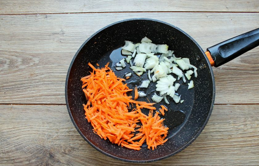 1. Этап. Говяжьи почки с картошкой: В сковороде разогрейте растительное масло и выложите резаный репчатый лук и нарезанную соломкой морковь. Обжаривайте все в течение 5-7 минут, перемешивая, на среднем огне.