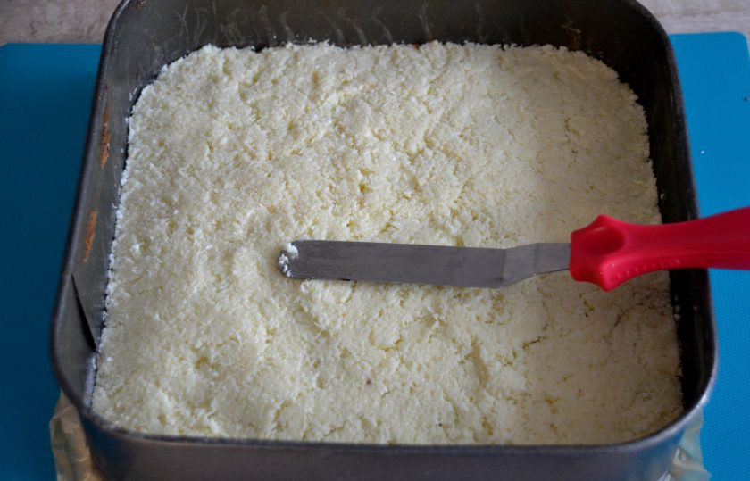 1. Этап. Пирожное Баунти: Для сборки снова поместите готовый бисквит в форму, выложите на бисквит кокосовую массу, слегка уплотните, разровняйте, поставьте в холодильник минут на 30-40 для стабилизации.