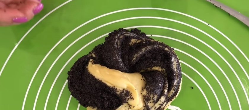 1. Этап. Булочки-плетенки с корицей и маком: 7. Сверните тесто в рулет, переверните швом вверх и разрежьте по шву напополам, не дорезая с одной стороны до конца. Выворачивая тесто маком вверх, сформируйте жгут. Скрепите концы плетенки и переложите на покрытый пергаментом противень.