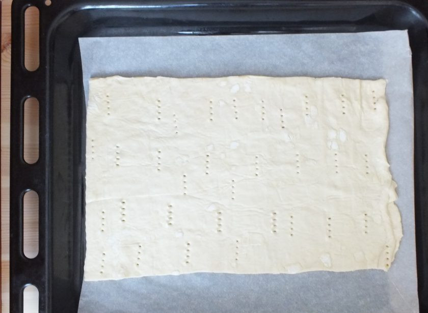 1. Этап. Пирожные с кремом и ягодами: Одну часть переложите на противень, застеленный пергаментной бумагой. Проткните вилкой. Поставьте выпекаться в горячую духовку при 200 градусов на 20 минут.