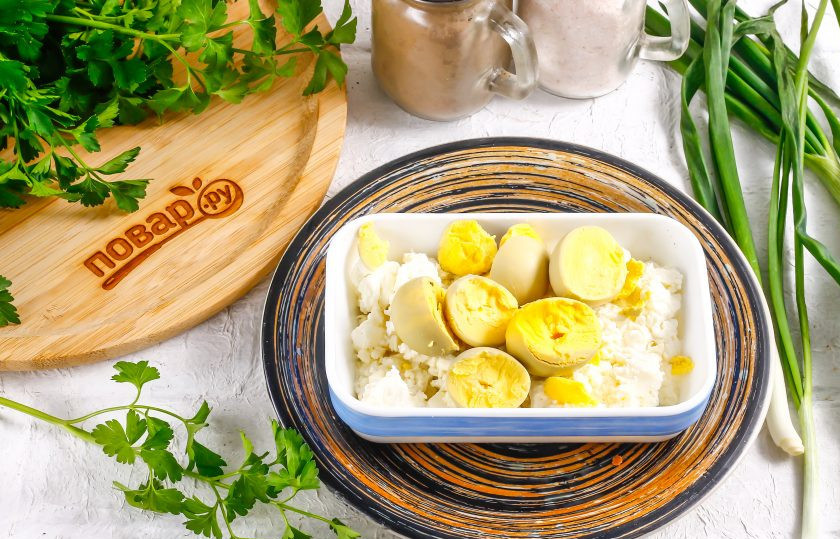 1. Этап. Яйца фаршированные творогом и зеленью: Отварные куриные яйца очистите от скорлупы и промойте в воде. Разрежьте каждое пополам, чтобы получились лодочки. В глубокую емкость выложите творог любой жирности, а на него — куриные желтки.