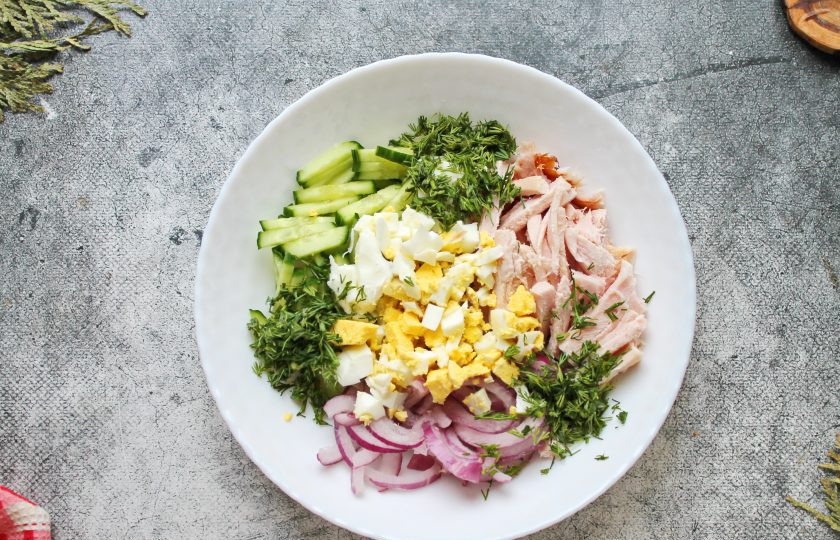 1. Этап. Салат из копченой куриной грудки с фасолью и огурцом: Вареное яйцо почистите, порежьте крупным кубиком, измельчите зелень. Выложите продукты в салатник.