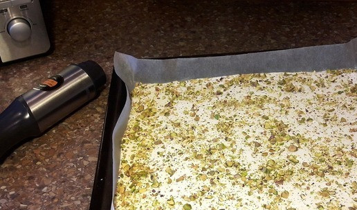 1. Этап. Меренговый рулет с ягодами и орехами: На противень расстелите пергамент. Распределите взбитые белки по пергаменту (толщина коржа должна быть равна примерно 2 сантиметрам) и посыпьте их фисташками. Отправьте в духовку на 140-160 градусов на 20 минут, а затем снизьте температуру до 100-120 градусов (зависит от вашей духовки) и готовить ещё 20 минут. Важно не пересушить меренгу — снаружи она должна быть сухой, а внутри мягкой, чтобы рулет не поломался при сворачивании