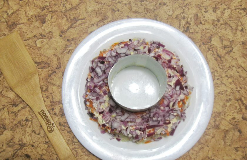 1. Этап. Салат Гранатовый браслет с языком: Фиолетовый или красный салатный лук мелко нарежьте и выложите на слой моркови. Этот слой смазывать майонезом не нужно.