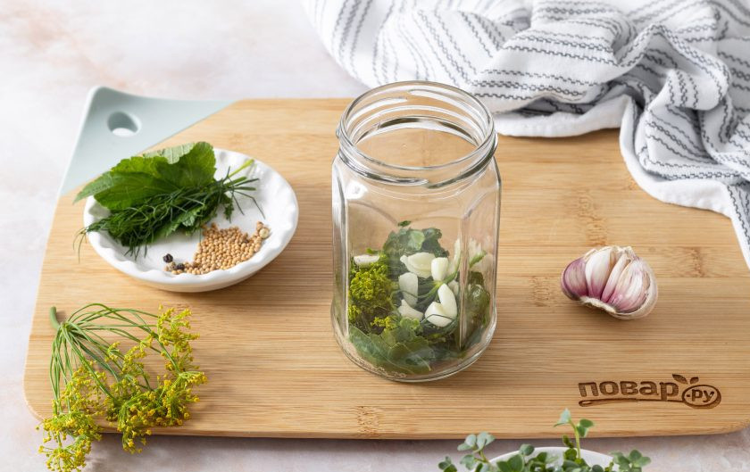 1. Этап. Маринованный зеленый горошек: На дно чистой стерилизованной баночки выложите промытую зелень и чеснок.