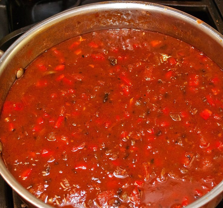 1. Этап. Сарсуэла: Вливаем туда же куриный бульон, тушим несколько минут на среднем огне. Потом добавляем к сосискам и бульону измельченные помидоры, зеленый перец, вино и специи. Перемешиваем и тушим минут 7.