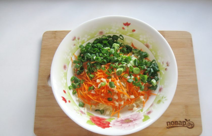 1. Этап. Капуста с чесноком и морковью: Зеленый лук помойте и мелко нарежьте. Выложите в салатник.