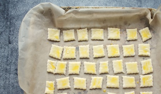 1. Этап. Закуска Малышки с тунцом: Немного посыпьте мукой стол и положите тесто. Не раскатывая, порежьте их на квадратики, чтобы можно было в дальнейшем просто положить в рот. Разложите на пергаменте на небольшом расстоянии, покройте и дайте постоять 20-30 минут, чтобы поднялись. Смажьте верх яйцом, только смотрите, чтобы яйцо не стекла на бока. Яйцо заклеит слои, и они не расслоятся.