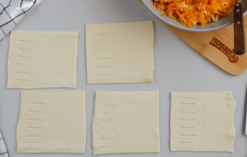 1. Этап. Тыква в слоеном тесте: Разверните тесто, раскатывать не нужно, просто порежьте его на квадраты. У меня два пакета теста по 500 грамм, получилось 20 квадратов. Каждый квадрат зрительно разделите на две части, в первой части острым ножом сделайте надрезы, как на фото.