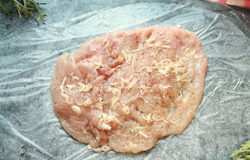 1. Этап. Куриный рулет с грибами, беконом и сыром: Куриную грудку, надрезая ножом, раскройте и отбейте в пласт. Посолите, поперчите и смажьте измельченным чесноком.