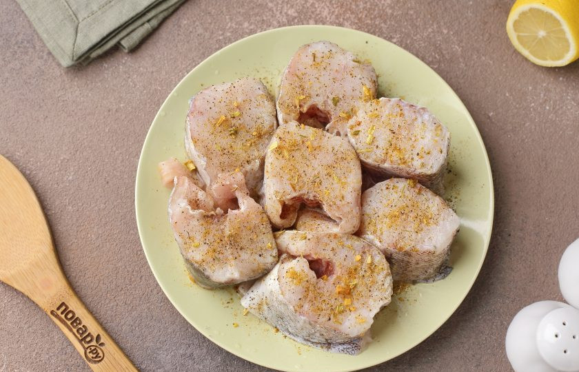 1. Этап. Минтай в сметане в мультиварке: У меня уже потрошённый минтай без головы. Дайте рыбе немного оттаять, чтобы она оставалась немного плотной и нарежьте её порционными кусочками. Срежьте плавники и обязательно удалите внутреннюю чёрную плёнку. Полейте готовые стейки соком лимона, натрите солью и специями.