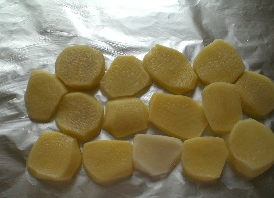 1. Этап. Плотва в духовке: Почистите картофель. Нарежьте его кружочками. Расстелите на противень фольгу для запекания. Выложите на неё половину нарезанного картофеля.