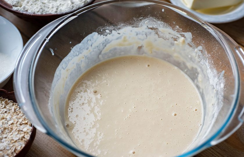 1. Этап. Булочки с овсяными хлопьями: Перемешайте венчиком до получения однородной смеси, которая по консистенции напоминает блинное тесто — это опара. Миску с опарой накройте кухонным полотенцем и оставьте в теплом месте на 30 минут.