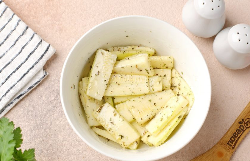 1. Этап. Кабачки дольками с сыром в духовке: Переложите кабачки в глубокую миску. Посолите, добавьте по вкусу специи и масло. Хорошо перемешайте.