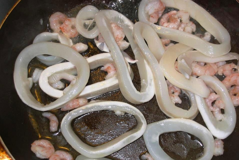 1. Этап. Паста с кальмарами: Кальмаров нарежьте кольцами, смешайте с креветками, посолите, полейте лимонным соком и оставьте на 15 минут. Затем обжарьте их на отдельной сковороде в течение 5 минут.