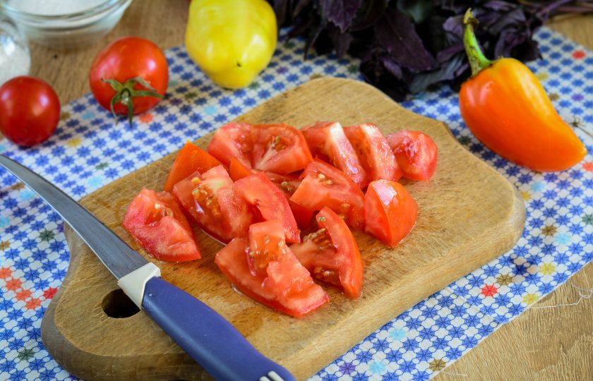 1. Этап. Лечо Счастливый день: Помидоры промойте, срежьте плодоножки и нарежьте овощи дольками.