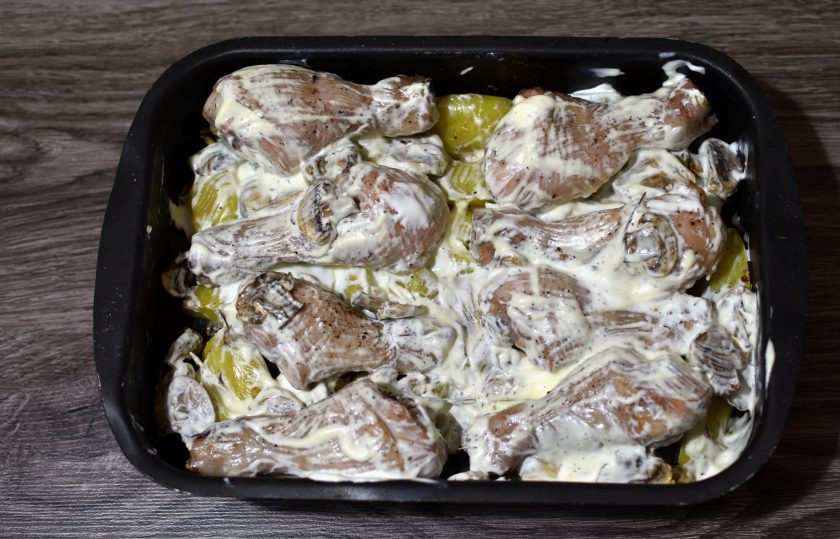 1. Этап. Куриные ножки с картошкой и грибами: Достаньте форму из духовки и залейте сметаной, подсоленной по вкусу и смешанной с тертым чесноком.