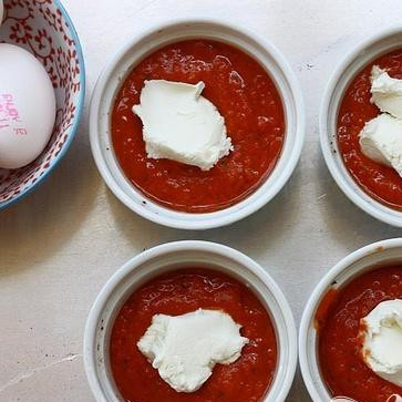 1. Этап. Запеченные яйца в томатном соусе: 5. Вылить 1/4 стакана теплого соуса в каждую из 8 форм для выпекания. Выложить сверху 2 чайные ложки козьего сыра.