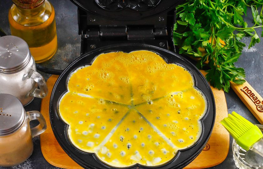 1. Этап. Омлет в вафельнице: Влейте часть яичной массы, не заливая за края панелей. Обжарьте примерно 2-3 минуты, не закрывая крышку, пока верхняя часть омлета не схватится, иначе масса выльется и за края, запачкает вафельницу.