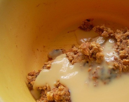 1. Этап. Шоколадная колбаса со сгущенкой: Возьмите любое печенье, лучше песочное. Поломайте его на мелкие кусочки и положите в миску. Добавьте к нему сгущенное молоко и растопленное сливочное масло. Чернослив также нужно мелко порезать и отправить к остальным ингредиентам. Добавьте также какао порошок.