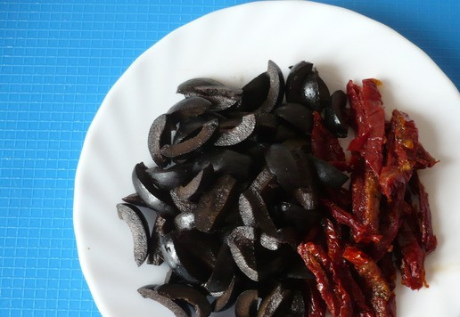 1. Этап. Закуска с тунцом на лепешке: Тонко нарежьте оставшиеся вяленые томаты, маслины без косточек нарежьте крупно.