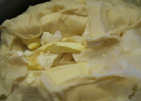 1. Этап. Выпечка из теста фило: 10. Так же сделайте «рулеты» из оставшихся пластов теста фило, разделяя каждый на 6 частей и равномерно распределяя начинку из творога. От третьего пласта отделите часть теста, оставьте его для верха пирога. Получившиеся «рулеты» выложите в форму в любом порядке. Между «рулетами» положите кусочки замороженного масла. Оставшиеся за пределами формы края теста фило заверните внутрь. Сверху накройте оставленным куском теста.