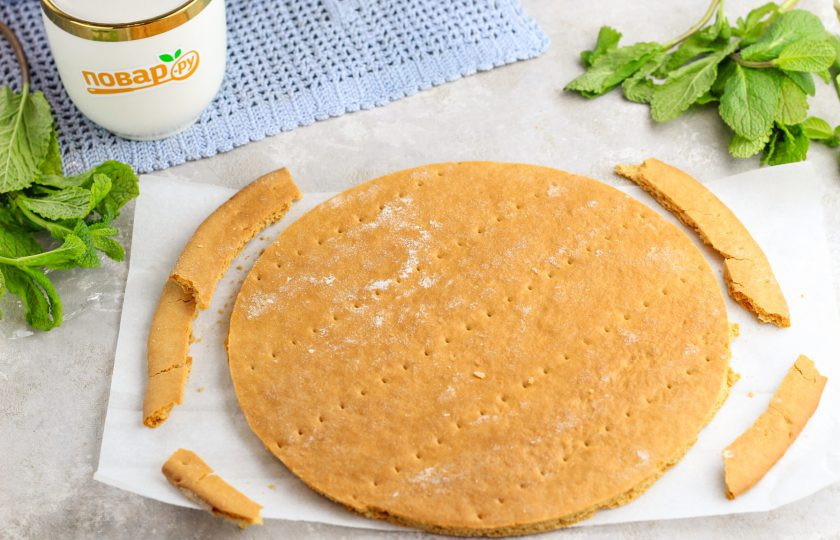 1. Этап. Медовик с вареной сгущенкой и сметаной: Разделите тесто на равные части и раскатайте их на пергаментной бумаге в округлые пласты. Испеките в прогретой до 180 градусов духовке по 5-7 минут до румяности и извлеките, остудите. Готовые коржи подрежьте при помощи тарелки, остатки не удаляйте.