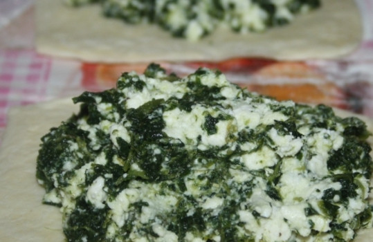 1. Этап. Пирожки с адыгейским сыром: 1. Тесто разморозим, раскатаем в тонкий пласт нарежем небольшими квадратиками (размером примерно 10 на 10). Нарезанный и измельченные шпинат с луком (если используете) смешаем до однородности, добавим к ним сметану и соль (по вкусу). У яйца отделяем желток от белка. Белок добавляем к начинке. Желток не выбрасываем, им мы будем смазывать наши пирожки для получения румянца.