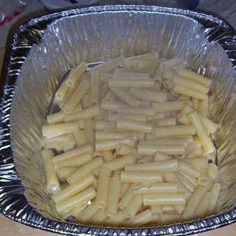 1. Этап. Тройной сырный Зити: Слейте воду из макарон. Поместите их в форму для выпечки.